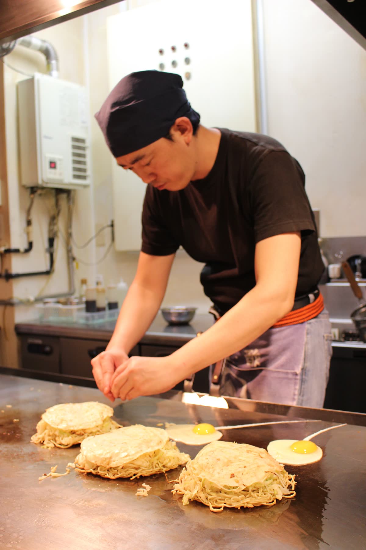 Hiroshima-style okonomiyaki cooking on a hotplate